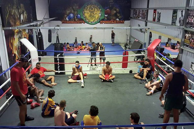 boxing-660.jpg A boxing ring with a group of young Aboriginal men seated in a circle and two older men standing