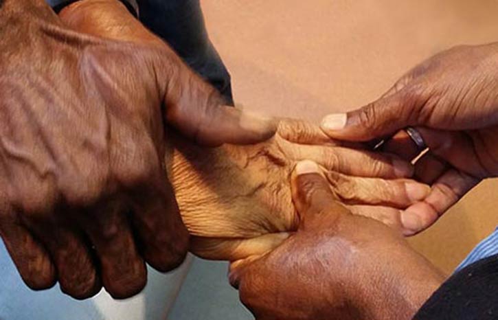 Two pairs of hands massaging a fifth hand