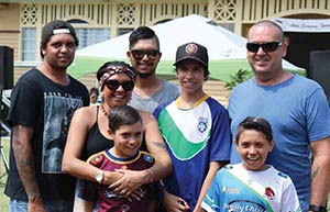 Aboriginal woman in a loving embrace with a group of men and boys