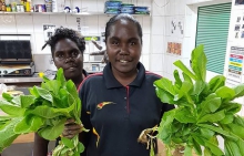 Two young women in a shop holding salad greens