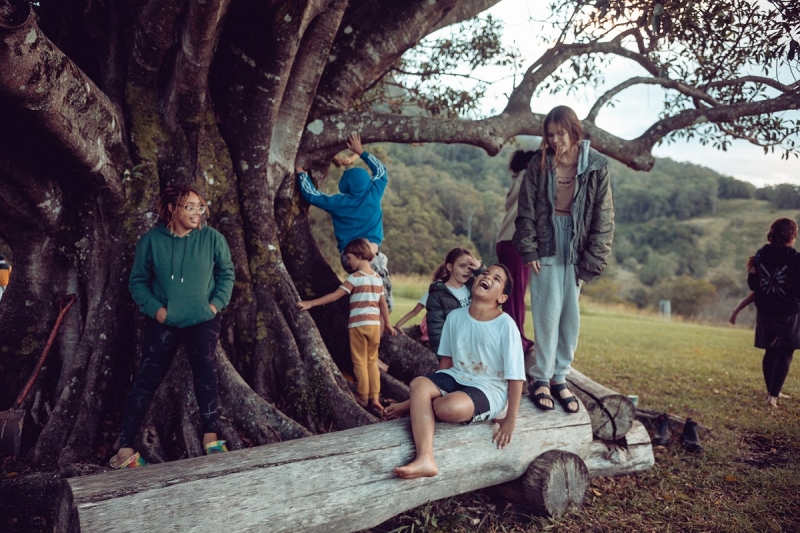 A group of children play beside a large tree