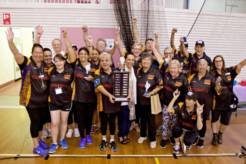 A group of people holding a large trophy and cheering