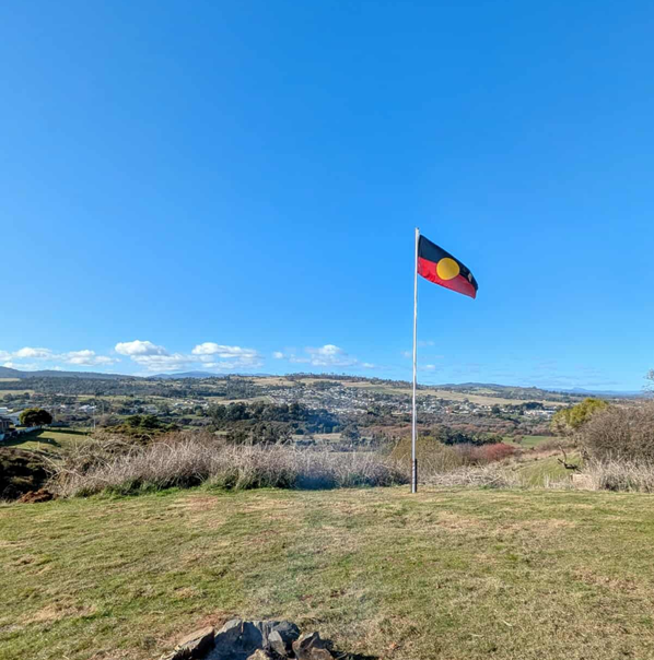 An Aboriginal flag flies in an area of open space