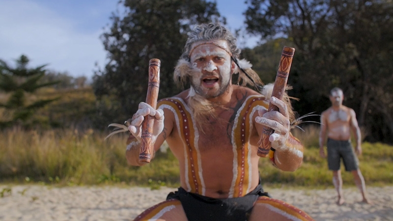 An Aboriginal man in body paint faces the camera