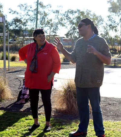 A man and a woman stand outdoors, talking