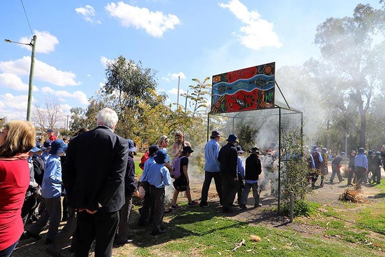 A large group of people file through an outdoor entryway with smoke