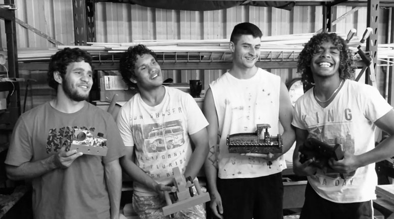 A black and white photo of 4 young people holding toys and smiling