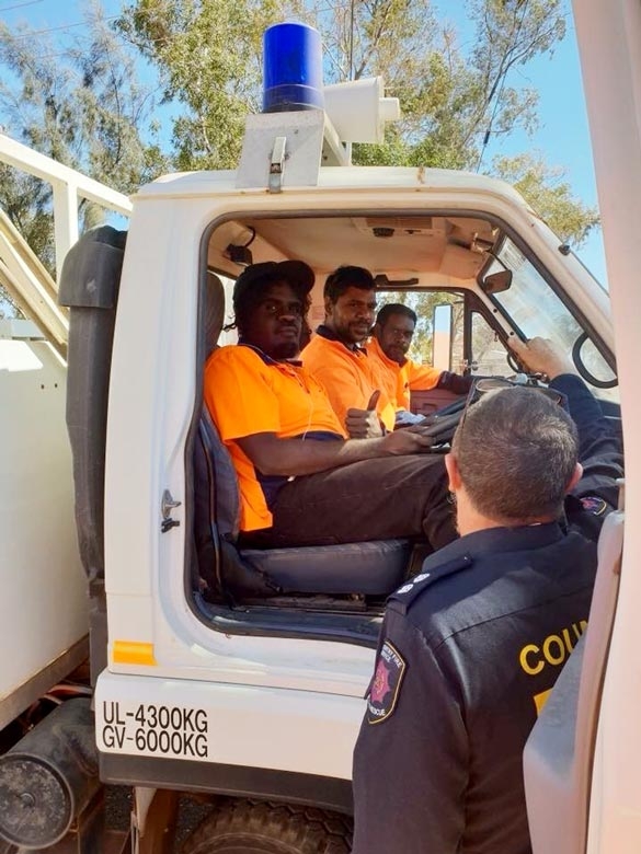 Three men sit in the cab of a white truck