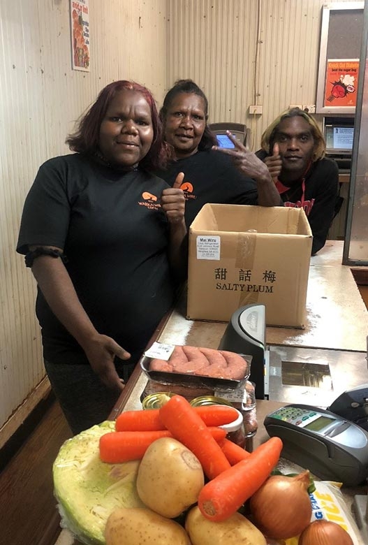 A small group in a kitchen smile at the camera