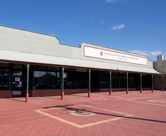 A building with a long verandah and red brick paving outside