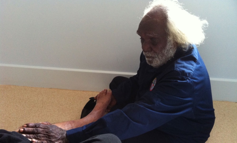 A man sits with a person lying on the floor