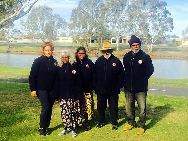 A group of 5 people stand outside posing for the camera