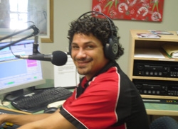 A man wearing headphones and sitting with a microphone
