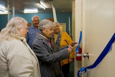 People cutting a ribbon over a door