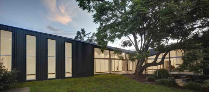 Two sides of a building around a lawn and tree