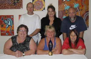 Six people with a trophy in front of them