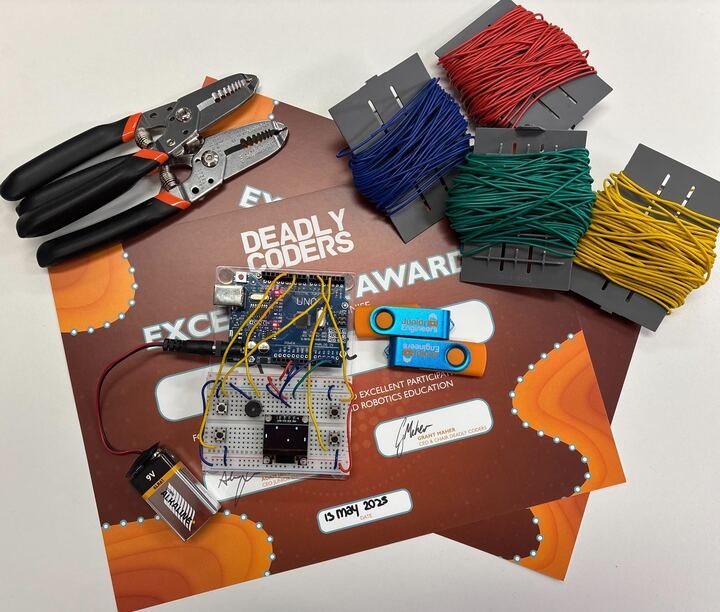 A number of computer components rest on a certificate with the words Deadly Coders Excellence Awards