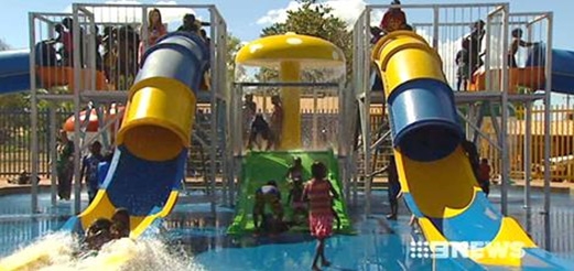 Two water slides with children playing nearby