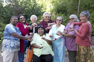 A group of women hold out their hands as though they are holding something between them