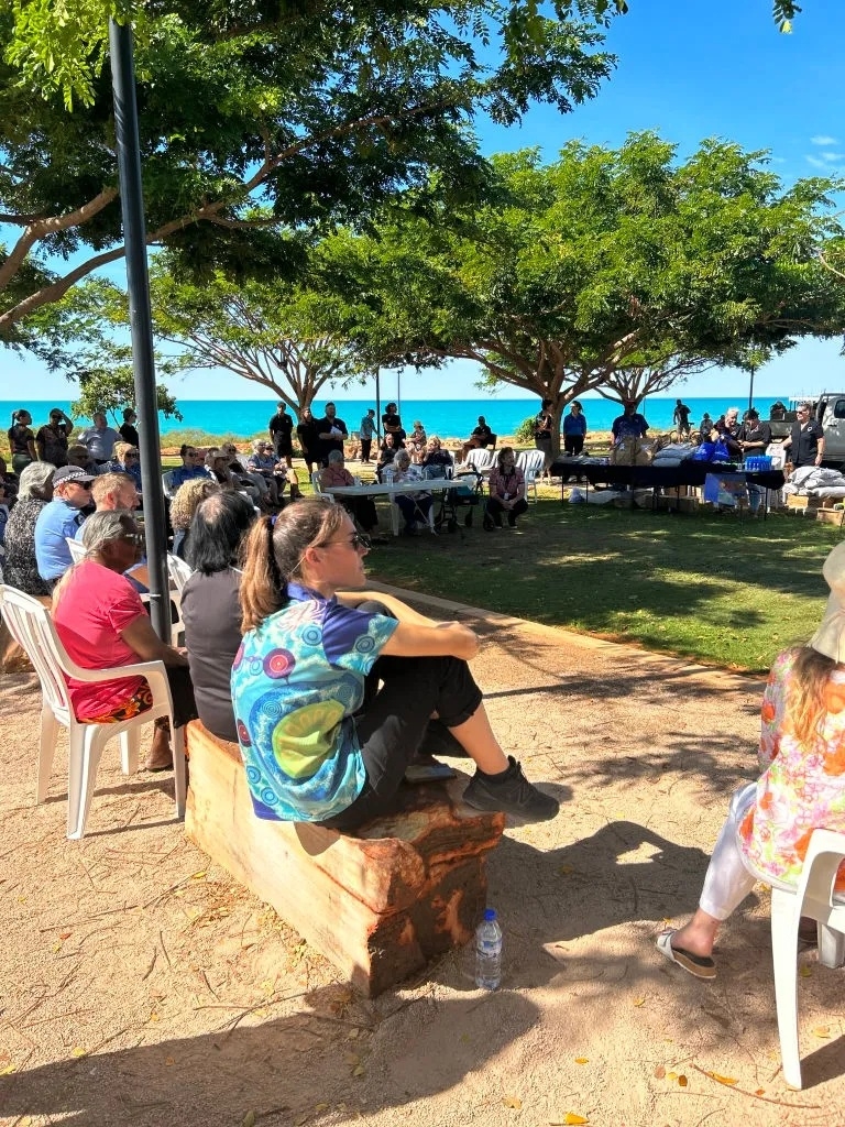 A group of people sit around a grassed area