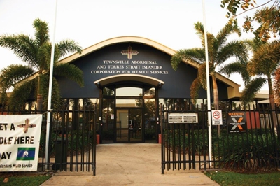 The front of a building with gates and palm trees in front of it