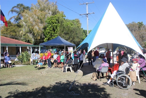An outdoor area with a number of people under and around marquees