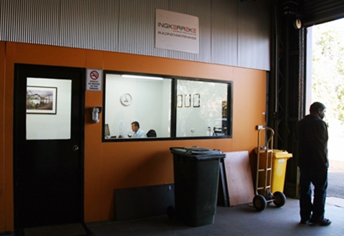 An internal orange wall with a door and windows looking into an office