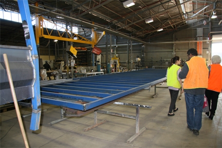 People in hi vis stand near a steel frame