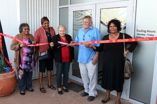 A group of people cut a ribbon in front of a building