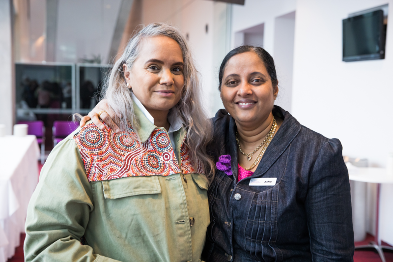 Two women standing close together and smiling