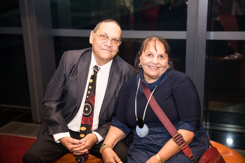 A man and a woman sitting close together and smiling at the camera