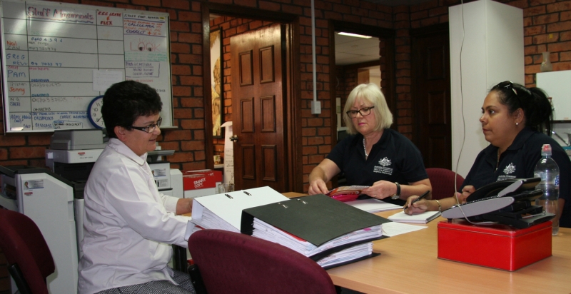 Three women sit around a desk