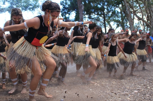 A group of women in black tops and grass skirts dancing