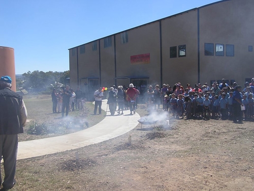 A large group of people near a building with smoke obscuring them