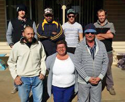 A small group of people poses outside a building