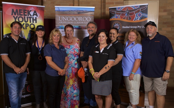 A group of people pose in front of banners for the Meeka Youth Expo