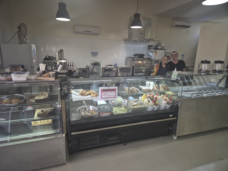 Two people stand behind food cabinets in a store